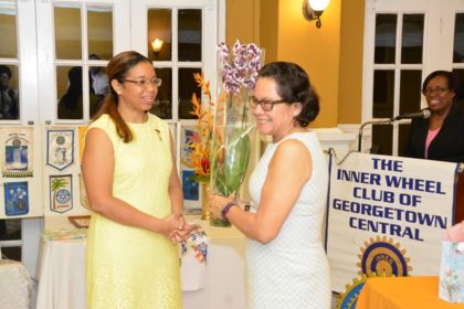 First Lady, Mrs. Sandra Granger smiles as immediate Past President of the Inner Wheel Club of Georgetown Central, Ms. Cherri Peters-Grant (first left) presents her with a bouquet of orchids in appreciation for her attendance at the induction ceremony. 