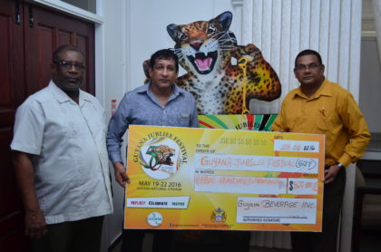 Senior Manager of Guyana Beverage Inc., Shawn Hera (center) presents a $500,000 cheque to Guyana Tourism Authority’s Director, Indranauth Haralsingh (right) and Permanent Secretary to the Ministry of Public Telecommunications, Derrick Cummings (left)