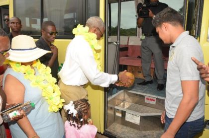 President David Granger pours coconut water to officially commission the 30-seater bus, while Minister of Social Cohesion, Ms. Amna Ally looks on. Sajid Baksh, a representative of the donor, Mr. Suresh Jagmohan is at right. 