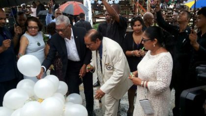 President David Granger and Prime Minister Moses Nagamootoo and their spouses write messages of unity and peace on while balloons 