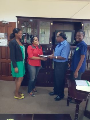 Chief Executive Officer of NAREI, Dr. Oudho Homenauth presents a copy of the contract to a representative of S&K Construction Services. Also in the picture are head of the Mangroves Department Kene Moseley and NAREI's Engineer Luandra Jack