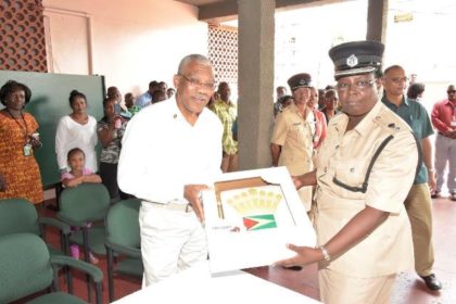 President David Granger receives a cake, with the Guyana Flag and the Presidential Standard symbol from a representative from the Guyana Police Force