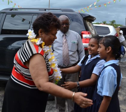 Two students greet Minister of Social Cohesion, Ms. Amna Ally at the Blairmont Primary School