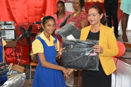 Ms. Varisty Raywat receives her backpack from Ms. Pamela Nauth, Technical Officer from the Ministry of Social Cohesion