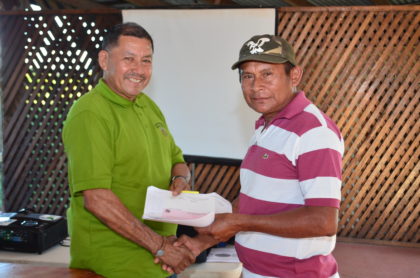 Minister of Indigenous Peoples’ Affairs, Sydney Allicock handing over a cheque to a toshao of one of the beneficiary villages