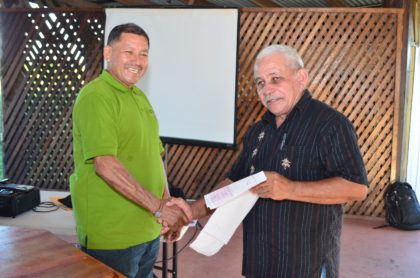 Minister of Indigenous Peoples’ Affairs, Sydney Allicock handing over a Jubilee grant cheque to another toshao