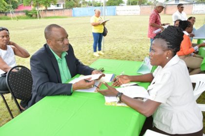 Minister of State, Mr. Joseph Harmon listening to this resident explain her challenges during the Meet the Public event at the Mckenzie Sports Club Ground in Linden today.