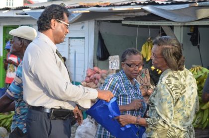 Public Security Minister, Khemraj Ramjattan distributing fliers and other items to raise awareness of trafficking in persons to members of the public around the Bourda Market area.