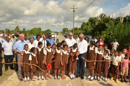 Students of the Parika Primary school help the President to cut the ceremonial ribbon for the opening of the Parika Paved Road, which is 8.2 km long