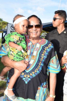 Prime Minister Moses Nagamootoo poses with a child dressed in her traditional African attire