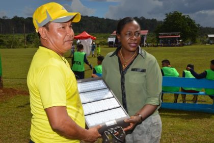 Minister within the Ministry of Education, Ms. Nicolette Henry officially hands over the floodlights to a member of the District Sports Council.