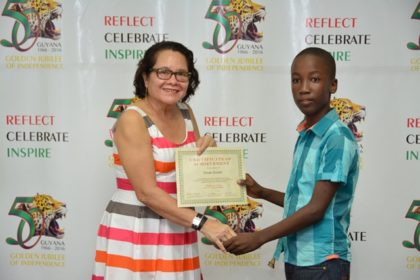 First Lady, Mrs. Sandra Granger presents a Certificate of Achievement to Master Omari Smartt, who graduated from the workshop held at the Friendship Primary School, Friendship, East Coast Demerara.   