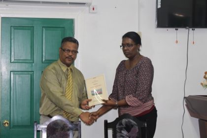 Chief Labour Officer of the Ministry of Social Protection, Charles Ogle handing over the report of the investigation into the death of Owen Morris, to the Human Resources Personnel of John Fernandes Limited, Donna Roberts-Benjamin