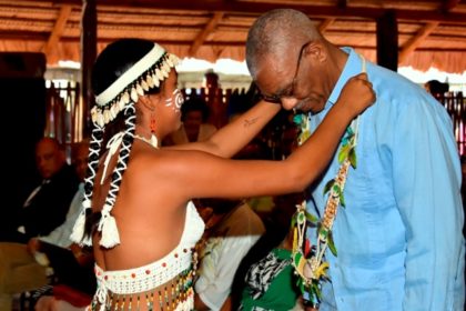 An Indigenous girl garlands President David Granger at the National Exhibition Centre at the launch of Indigenous Heritage Month. 