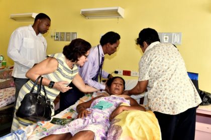 First Lady, Mrs. Sandra Granger helps the attending physician and another visitor to ease Ms. Ophelia James into a more comfortable position on her bed at the Georgetown Public Hospital Corporation.