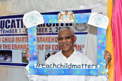 President David Granger holding up the "Each child matters" slogan 
