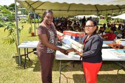 Minister within the Ministry of Education, Ms. Nicolette Henry handing over sports gear to Head Teacher (ag) Ms. Karen Basdeo 