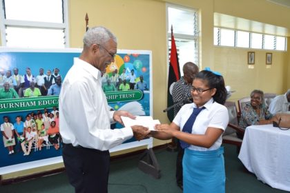 President David Granger presenting Ms. Jeanelle Fredericks with her bursary award. Ms. Fredericks, who hails from Upper Takutu-Upper Essequibo (Region Nine) is from the 2012 batch of awardees. She is now a fifth form student at the St. Joseph's High School  