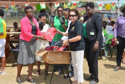 First Lady, Mrs. Sandra Granger presents a box of ‘the shoes that grow’ to a representative of the Kwakwani Primary School.