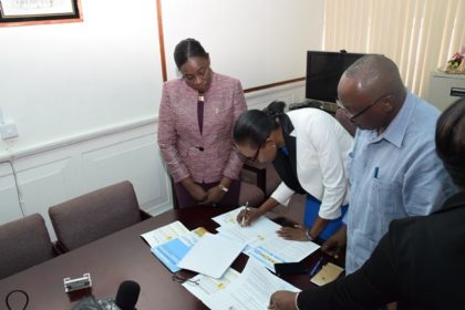 Minister within the Ministry of Education, Nicolette Henry along with Ava Marie Lindie of Alpha and Omega Community Health Associates signing the grant and Trevor Thomas, board member of Global Fund 